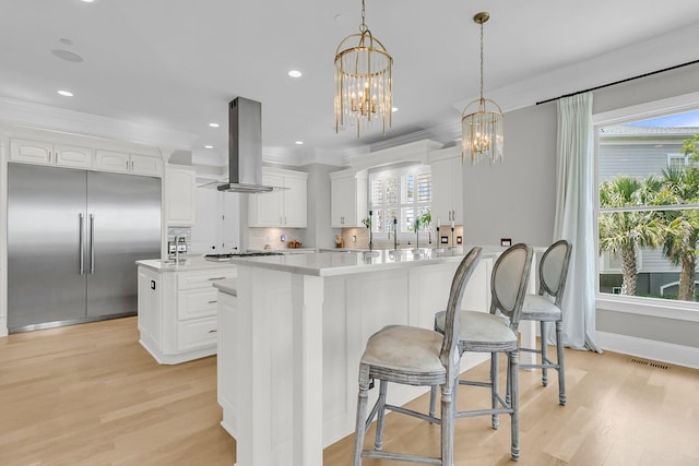 1720 Bowline Dr, Mount Pleasant, SC 29466 - kitchen featuring built in fridge, island range hood, light wood finished floors, light countertops, and crown molding