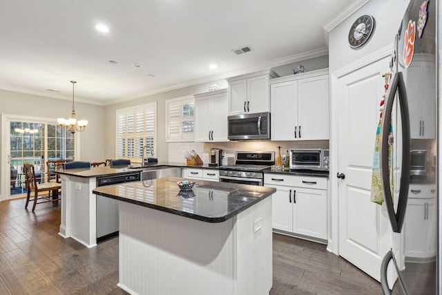 kitchen featuring visible vents, a peninsula, a sink, ornamental molding, and stainless steel appliances