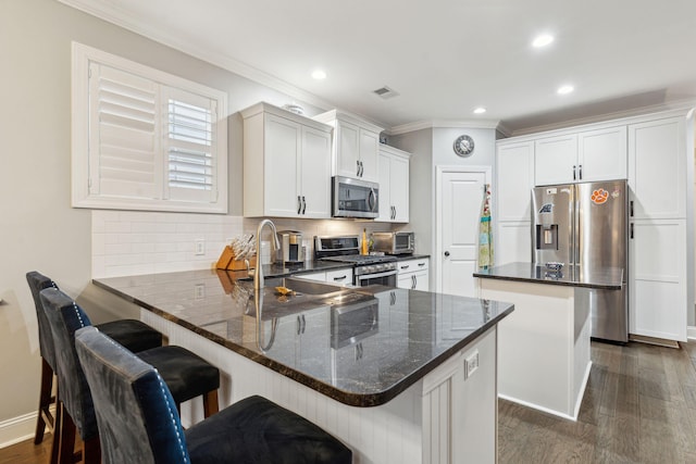 kitchen featuring a peninsula, stainless steel appliances, dark wood-type flooring, backsplash, and a center island