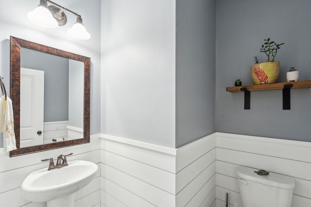 bathroom featuring wainscoting, toilet, and a sink