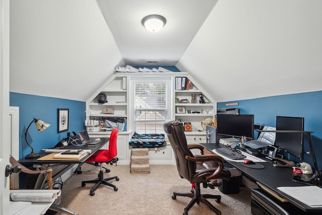 home office with carpet floors, built in shelves, and vaulted ceiling