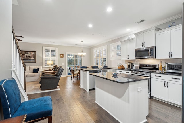 kitchen with a center island, open floor plan, a peninsula, dark wood-style floors, and stainless steel appliances