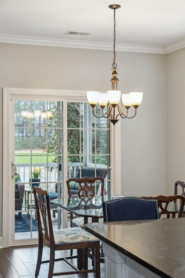 dining room featuring visible vents, a notable chandelier, hardwood / wood-style floors, and crown molding