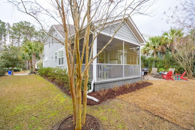 view of property exterior featuring a patio, a yard, and a sunroom