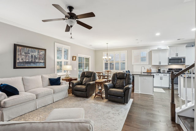 living area with dark wood finished floors, stairs, ornamental molding, recessed lighting, and ceiling fan with notable chandelier