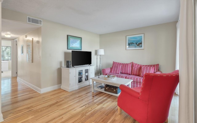 living room featuring wood finished floors, visible vents, and baseboards