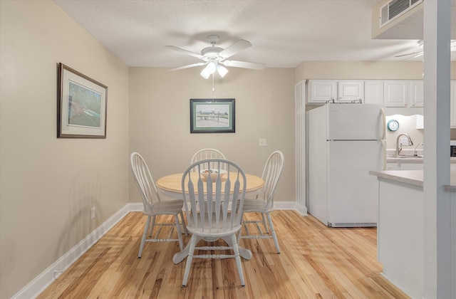 dining area with visible vents, baseboards, light wood-type flooring, and ceiling fan