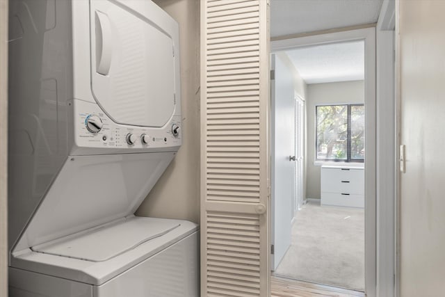 clothes washing area with laundry area, stacked washer and dryer, and light carpet