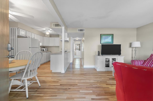 living area with visible vents, light wood-style flooring, baseboards, and ceiling fan