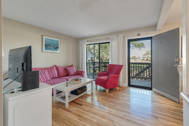 living room featuring beam ceiling and light wood-style flooring