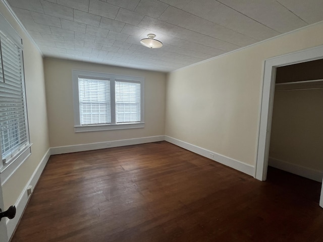 unfurnished bedroom featuring a closet, ornamental molding, and dark hardwood / wood-style floors