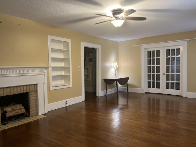 unfurnished living room featuring french doors, a textured ceiling, dark hardwood / wood-style floors, built in features, and a fireplace