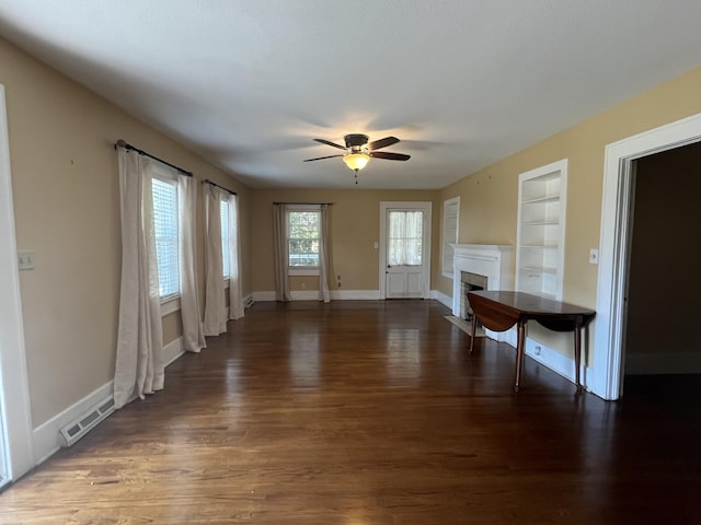 unfurnished living room featuring dark hardwood / wood-style floors, built in features, and ceiling fan