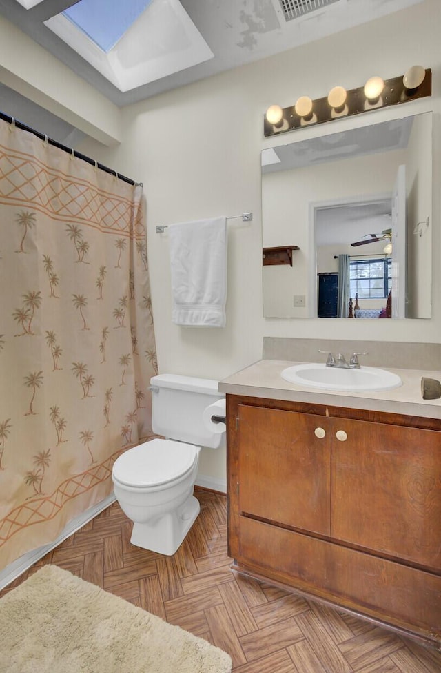 bathroom featuring parquet flooring, toilet, a skylight, vanity, and a shower with shower curtain