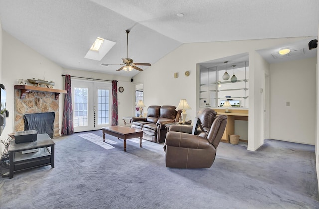 carpeted living room featuring lofted ceiling with skylight, a textured ceiling, ceiling fan, and french doors