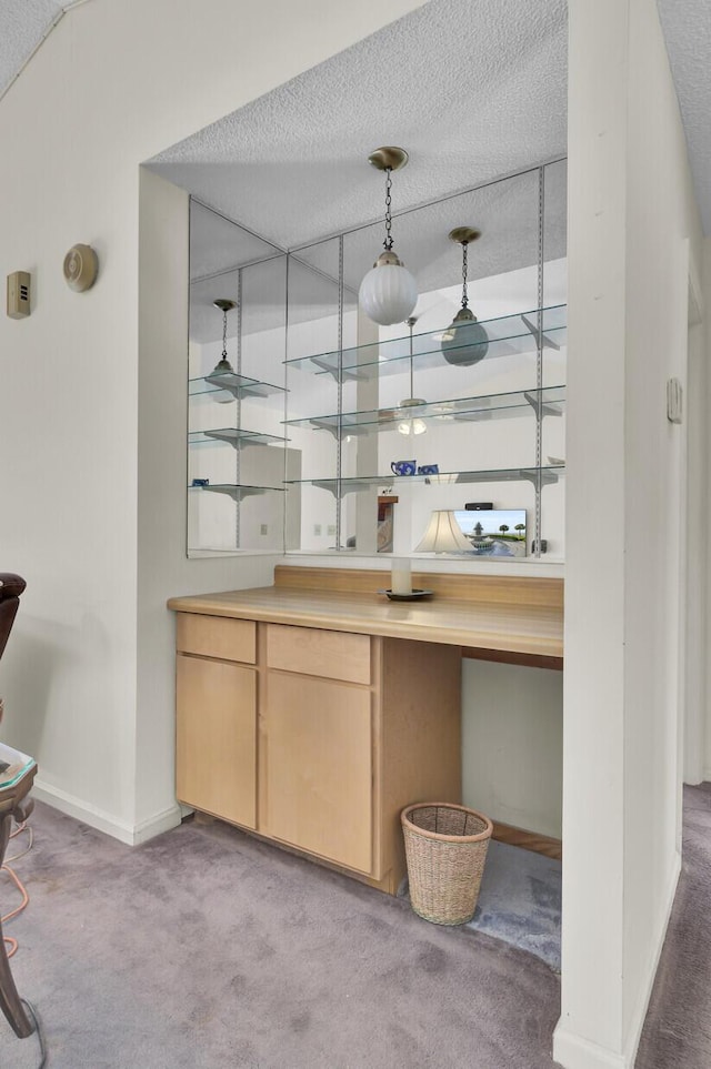 bar with hanging light fixtures, light colored carpet, a textured ceiling, and light brown cabinets