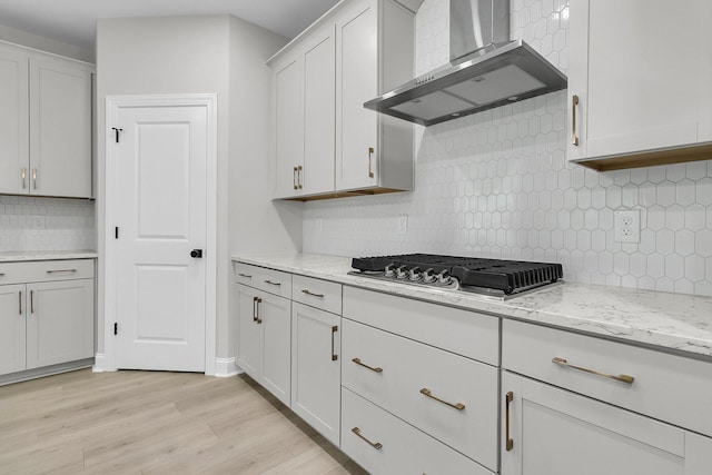 395 Wappoo Trace Ln, Summerville, SC 29486 - kitchen featuring wall chimney exhaust hood, backsplash, stainless steel gas cooktop, light wood-style flooring, and light stone countertops
