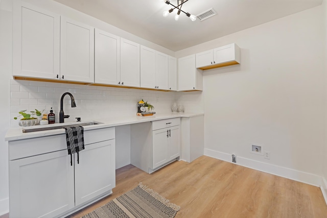 2608 Seymour Ave, North Charleston, SC 29405 - kitchen with decorative backsplash, light wood-style flooring, light countertops, and white cabinetry