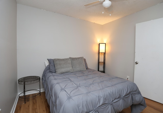 bedroom with ceiling fan, wood-type flooring, and a textured ceiling