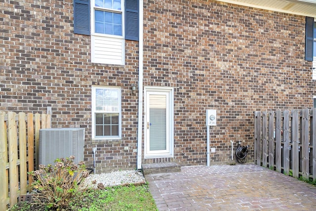 view of exterior entry featuring a patio and cooling unit