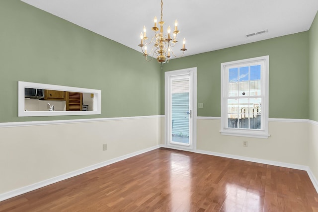 spare room featuring hardwood / wood-style floors and a notable chandelier