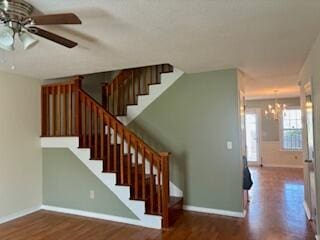 staircase featuring hardwood / wood-style floors and ceiling fan with notable chandelier