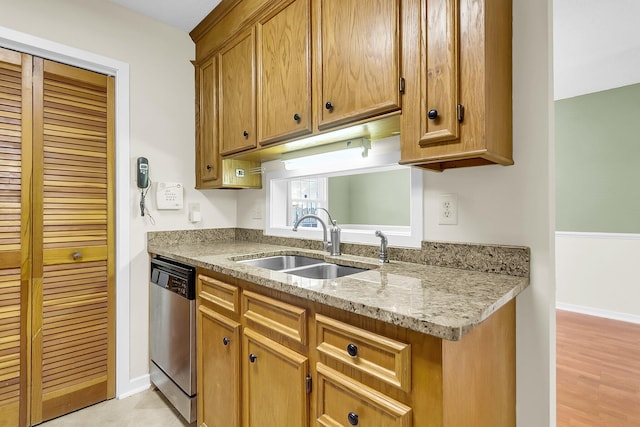 kitchen with light stone countertops, light wood-type flooring, stainless steel dishwasher, and sink