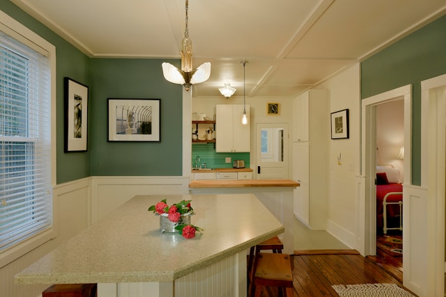 kitchen featuring sink, pendant lighting, white cabinets, dark wood-type flooring, and a breakfast bar area