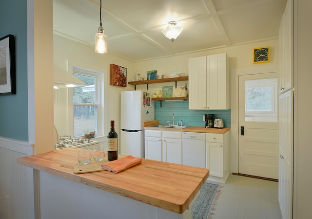 kitchen with kitchen peninsula, white cabinets, hanging light fixtures, butcher block counters, and white appliances