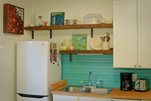 kitchen with sink, white refrigerator, and white cabinets