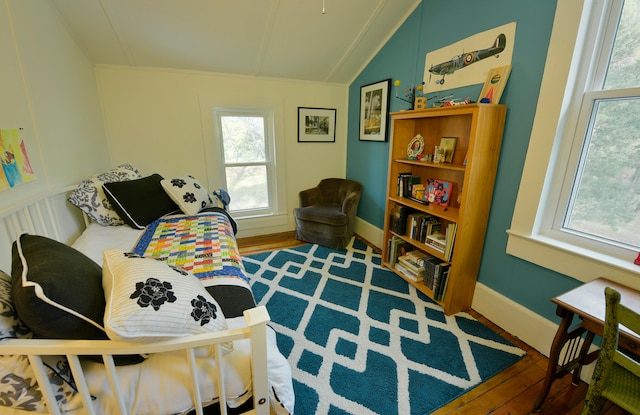 bedroom with multiple windows, hardwood / wood-style floors, and lofted ceiling