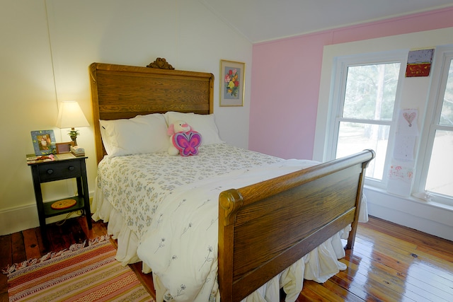 bedroom featuring lofted ceiling, wood-type flooring, and multiple windows