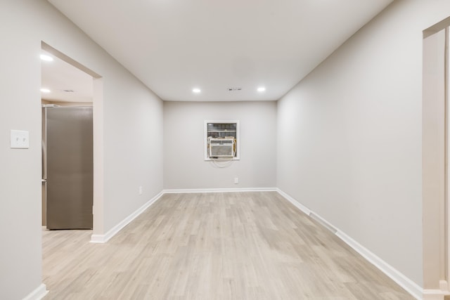 basement featuring stainless steel fridge, light wood-type flooring, and cooling unit