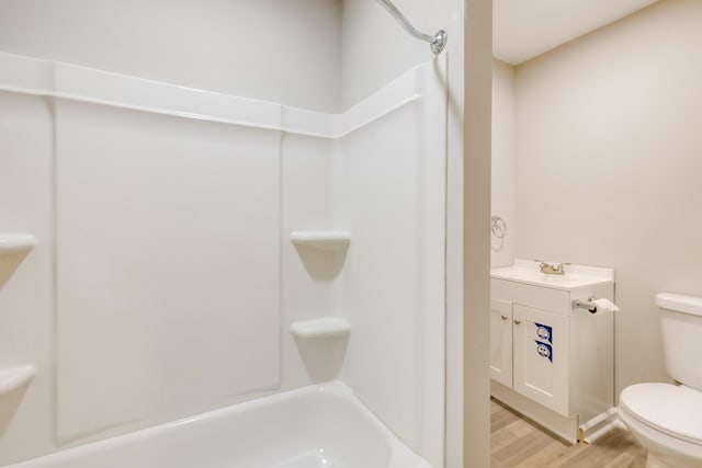 full bathroom featuring washtub / shower combination, hardwood / wood-style floors, vanity, and toilet