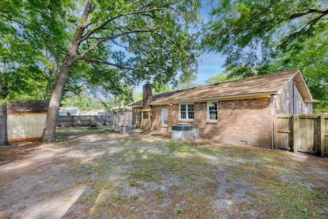 back of house with a fenced backyard, a chimney, brick siding, crawl space, and a storage shed