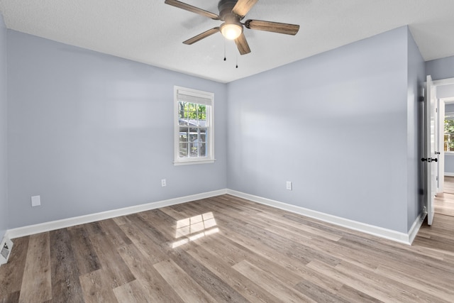 unfurnished room featuring baseboards, a ceiling fan, wood finished floors, and visible vents
