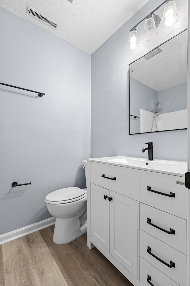full bath featuring visible vents, vanity, wood finished floors, toilet, and walk in shower
