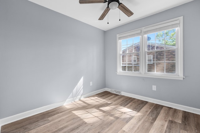 unfurnished room featuring baseboards, ceiling fan, wood finished floors, and visible vents