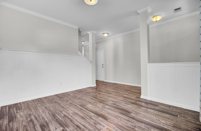 unfurnished room featuring visible vents, crown molding, decorative columns, wainscoting, and wood finished floors