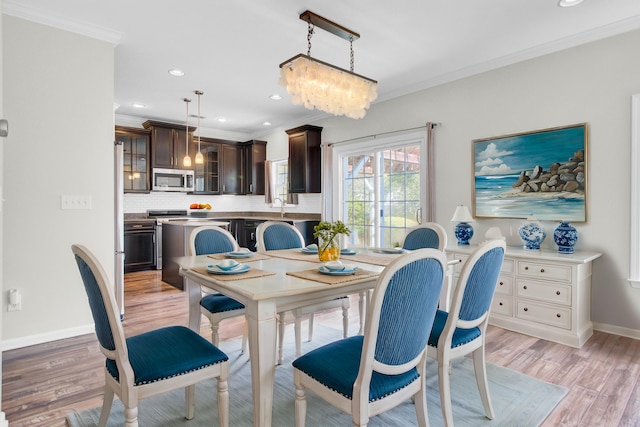 dining space featuring baseboards, recessed lighting, ornamental molding, light wood-style floors, and a chandelier