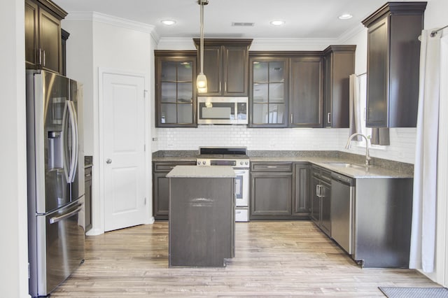 kitchen featuring light wood-type flooring, a sink, a center island, dark brown cabinetry, and appliances with stainless steel finishes