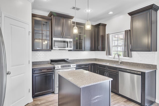 kitchen with a sink, appliances with stainless steel finishes, ornamental molding, and light wood finished floors