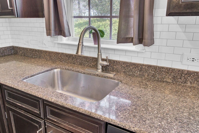 details with dark stone countertops, dark brown cabinets, backsplash, and a sink