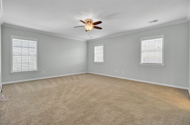 carpeted spare room with crown molding, visible vents, and ceiling fan