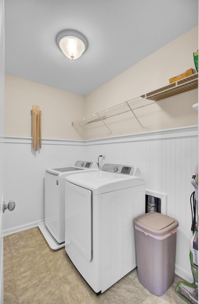 washroom featuring independent washer and dryer, wainscoting, and laundry area