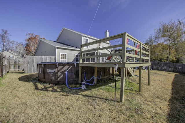 rear view of house featuring a swimming pool side deck and a lawn