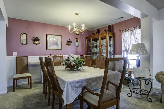 carpeted dining space featuring an inviting chandelier