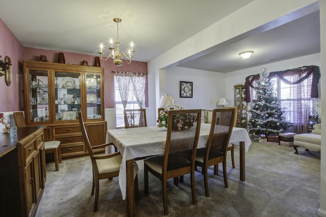 carpeted dining area with an inviting chandelier