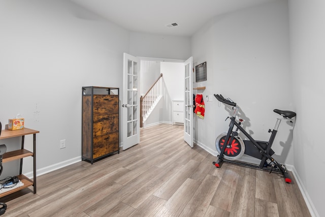 workout room with french doors and light hardwood / wood-style flooring