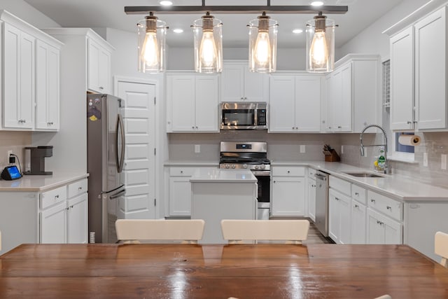 kitchen featuring decorative light fixtures, stainless steel appliances, white cabinets, and sink